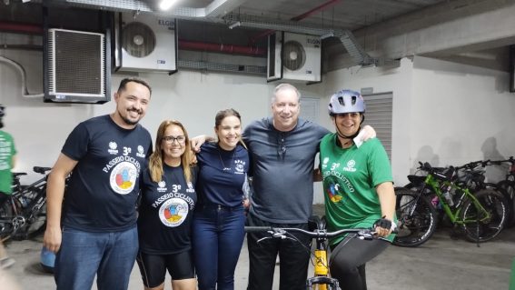 Pessoas posando para foto com bicicleta Descrição gerada automaticamente